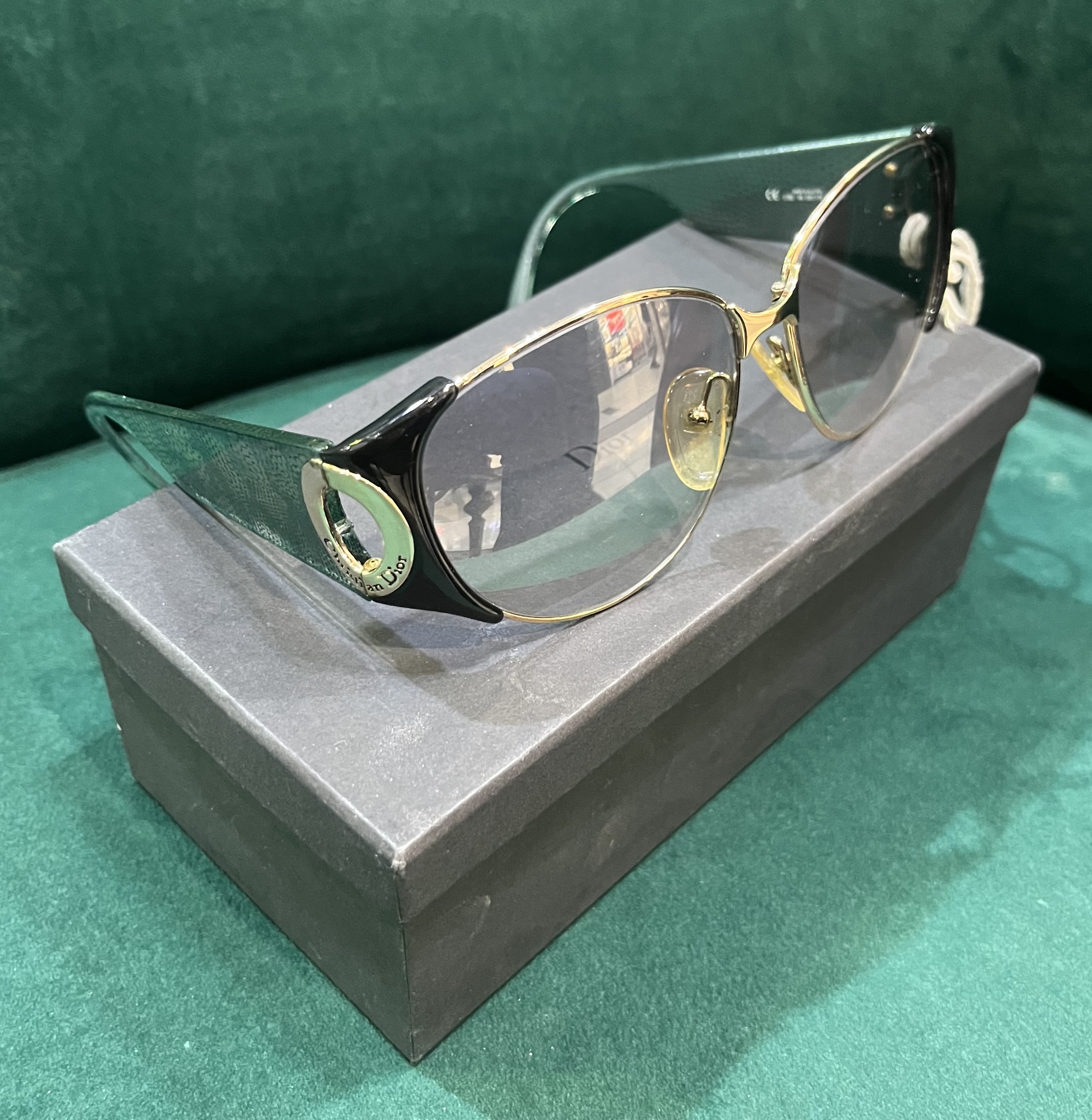 Pair of Christian Dior sunglasses with gold tone metal frames and wide green snake skin design acetate arms and gold tone hardware