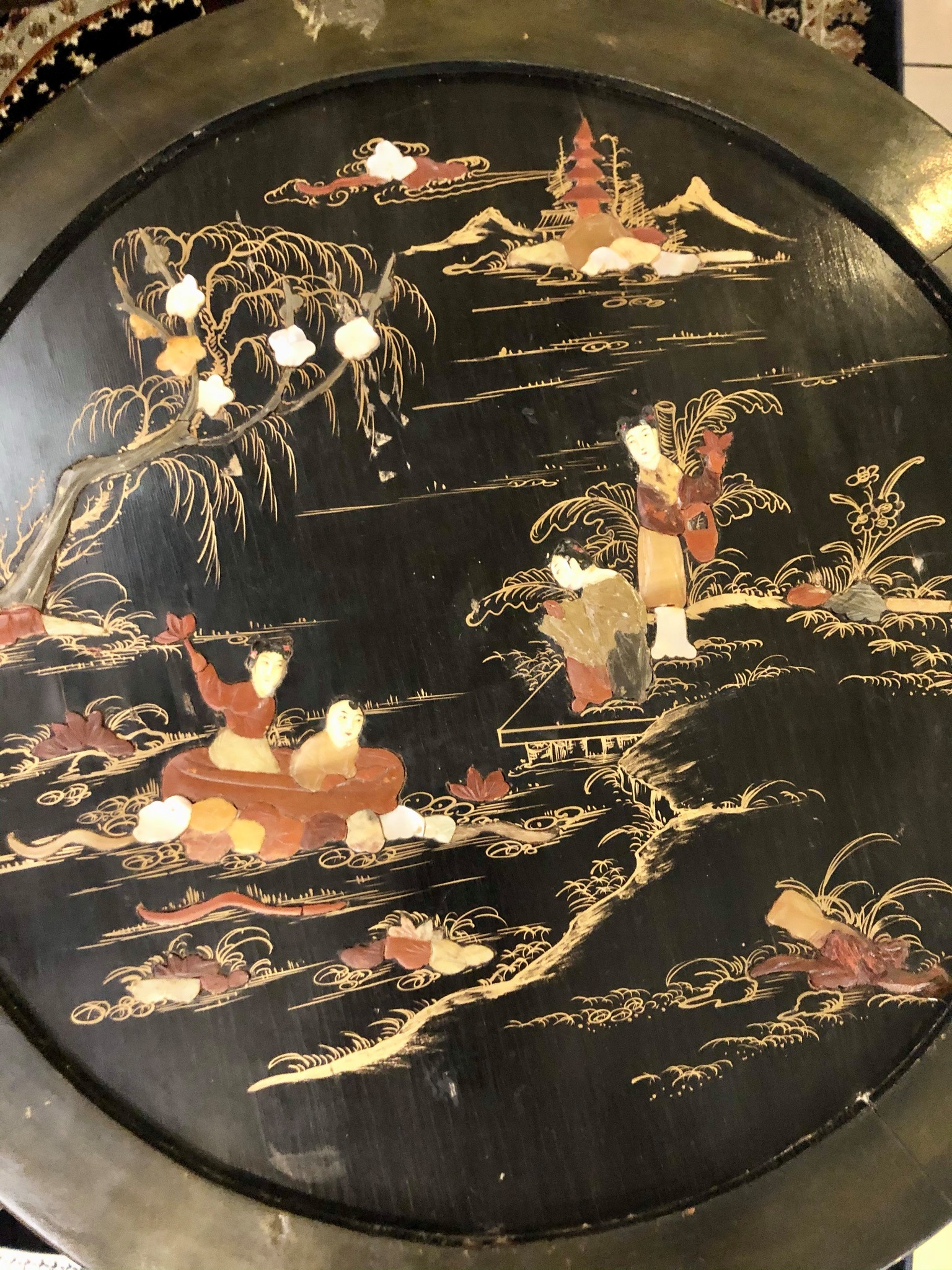 A round antique Chinese black lacquer foldable low coffee table with inlaid pearl and stone pictures. Size: 0.51m (height) x 0.66m (diameter width)  Price: R6,000.00