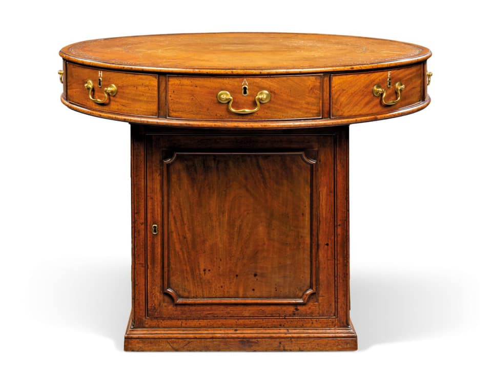 A GEORGE III MAHOGANY DRUM TABLE, CIRCA 1765, The circular leather-lined top above an arrangement of eight drawers inlaid with ivory letters 'L, E, H, A, F, R, LA, B', on a pedestal base with two doors and two false doors with cut-cornered panels, on a moulded plinth, with printed label 'III' beneath the top, 30 in. (76 cm.) high; 37 ½ in. (95 cm.) diameter. Estimate: 10,000 - 15,000 GBP. SOLD for 12,500 GBP